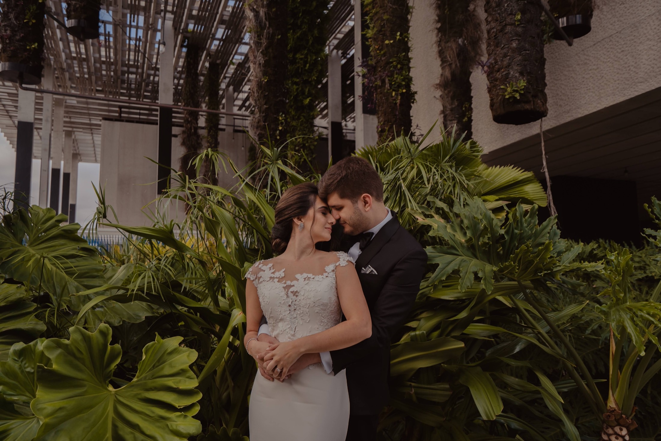 Novios frente a frente entre vegetación tropical el día de su boda en México.