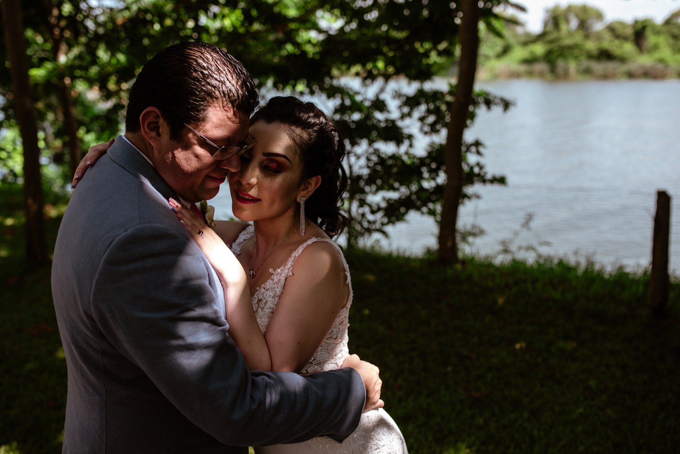 Novios abrazados junto al río rodeados de naturaleza en una boda en Veracruz.