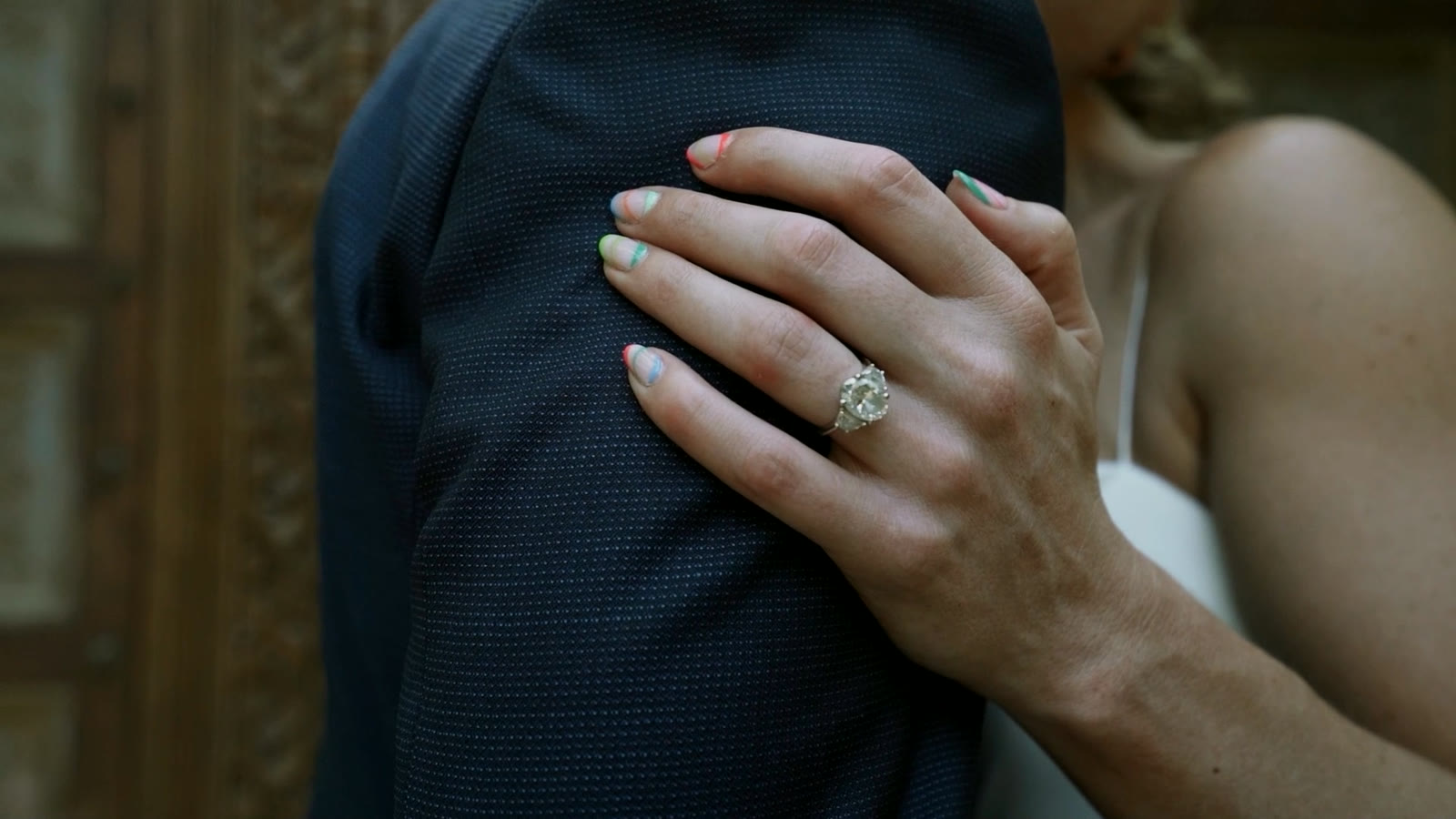 La mano de la novia con su anillo de compromiso sobre el pecho del novio